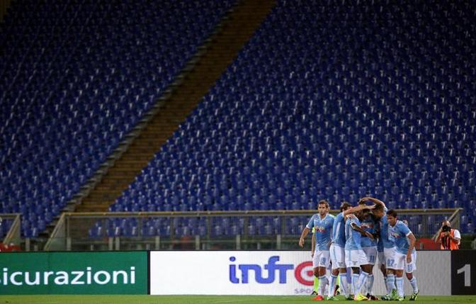 I giocatori della Lazio esultano per il gol dell'1-0 di Hernanes con la curva vuota alle loro spalle. Ansa